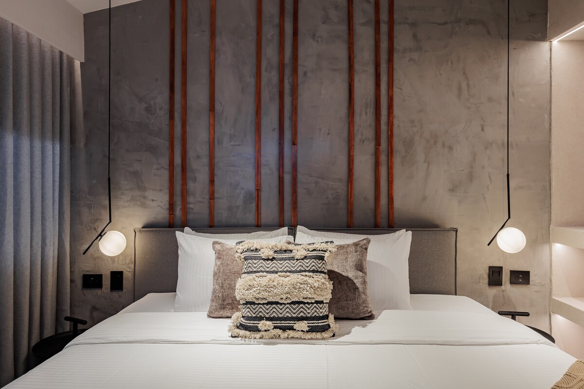 חדר שינה מרווח עם מיטת קינג סייז, מיזוג אוויר וטלוויזיה חכמה. חלל מעודן ונוח המיועד לשהייה רגועה ופרימיום