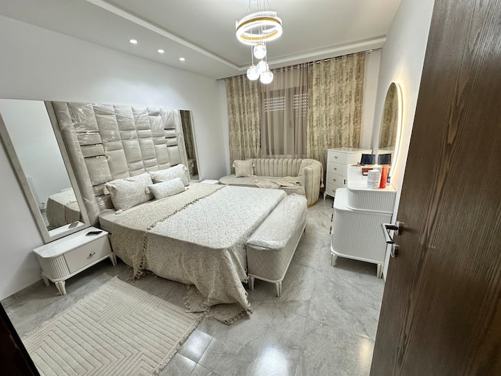 Habitación principal luminosa con cama King Size, tocador retroiluminado y zona de descanso