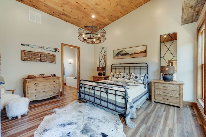 Пространа главна спална соба со засводени тавани и големи прозорци.