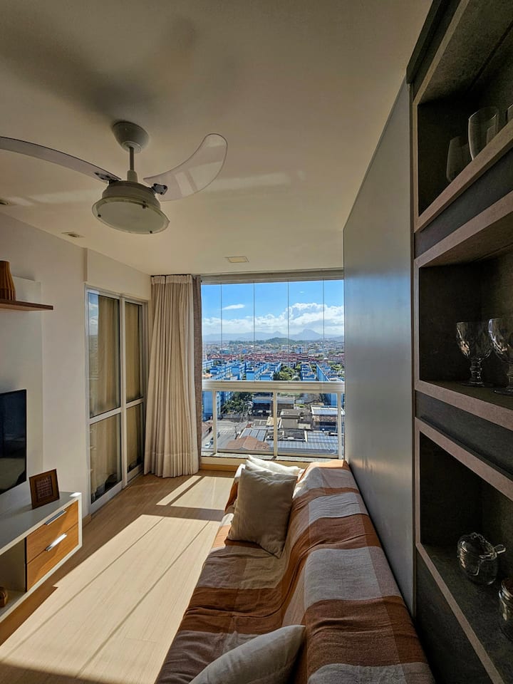 Acogedor salón con decoración moderna, amplio sofá, abundante luz natural y detalles en madera que crean un ambiente elegante y relajante.