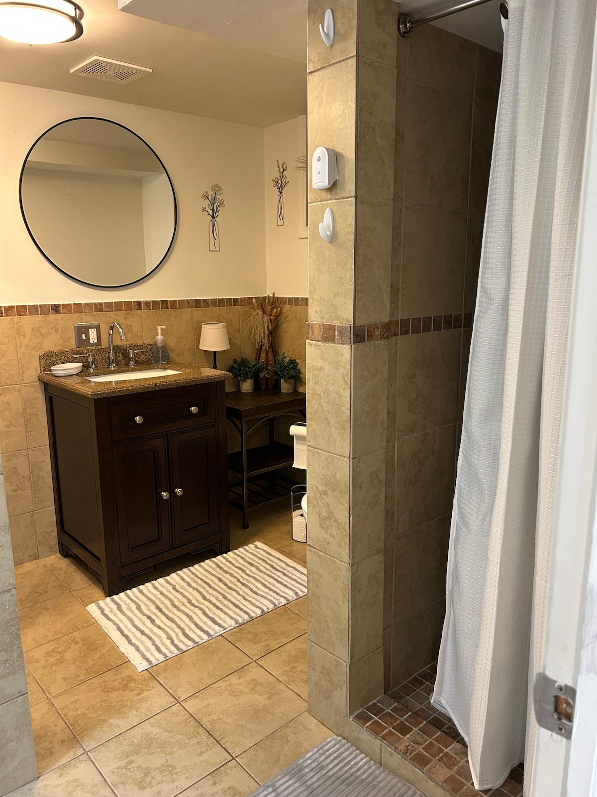 Bathroom — round mirror, granite vanity, tiled shower