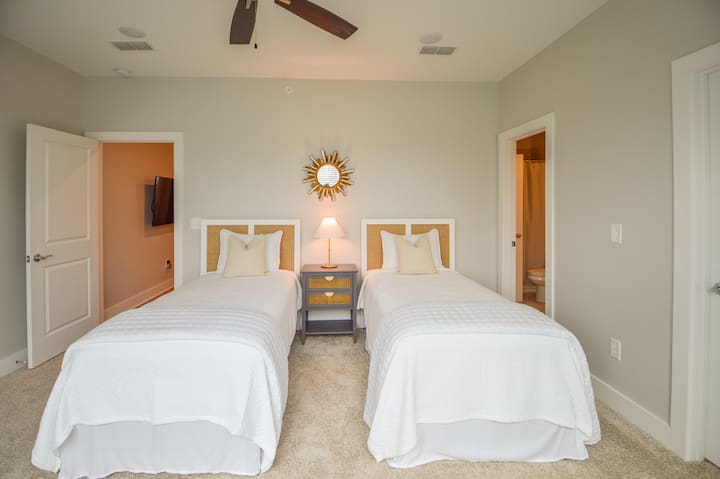 Chumba hiki kina vitanda viwili viwili vilivyounganishwa na stendi ya karibu iliyo na taa za ziada na sehemu ya kuchaji.