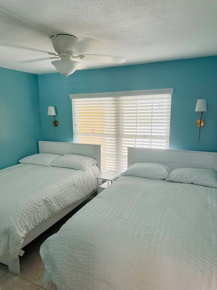 Dva bračna kreveta s luksuznom posteljinom i ventilatorom iznad glave.