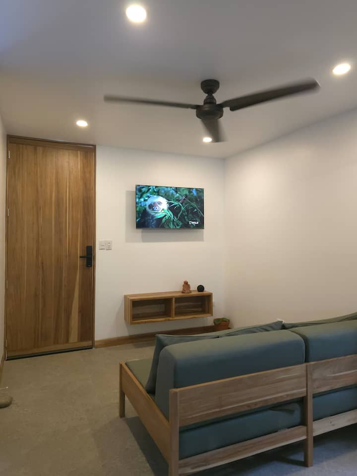 Всекидневна с телевизор, вентилатор на тавана и фотьойли