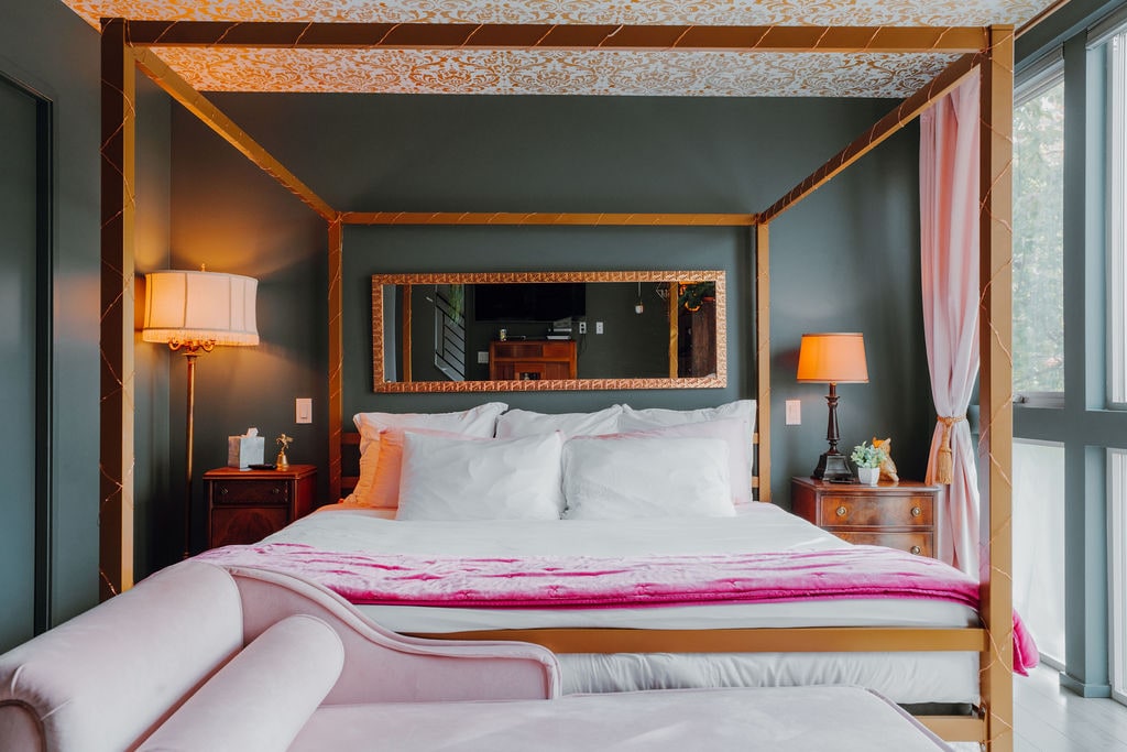 ️Tërheqje magjepsëse mjeshtërore — Çlodhu në krevatin mbretëror me shtroja pambuku premium, të kornizuara nga një tendë ari dhe tavan i modeluar. Muret blu të errët, thekse rozë, dekor retro, tavolina anësore elegante dhe një pasqyrë e madhe përfundojnë këtë arratisje nga Regjenca e Hollivudit.
