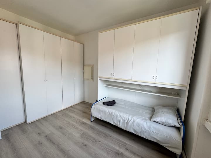 Habitación individual luminosa y minimalista con mucho espacio de almacenamiento y una cama acogedora. Un espacio tranquilo y funcional perfecto para descansar, leer o trabajar en total tranquilidad. Hay espacio para un colchón de aire adicional o una cuna.