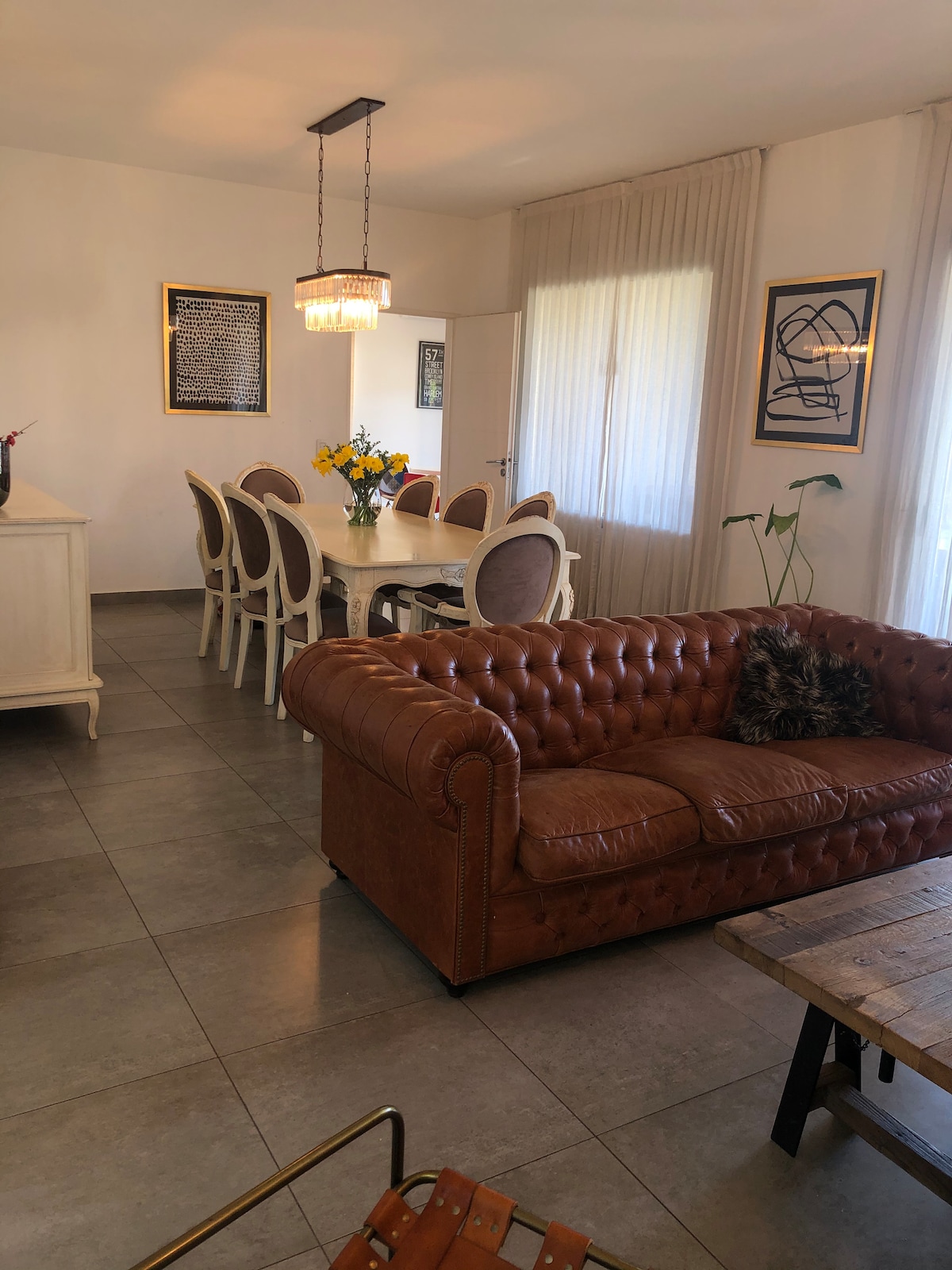 סלון משולב, מרווח ומואר, עם ספה מעור, שולחן לשמונה, חלונות עם וילונות שקופים ופרטי נוי. יש לו גישה ישירה לגלריה ולפארק, אידיאלי לפגישות ולבילוי בחוץ