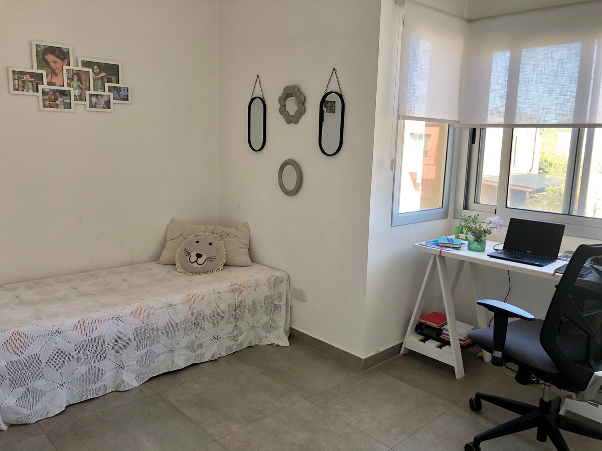 חדר שינה מואר עם שולחן, מיטת יחיד וחלון גדול המספק אור טבעי. יש בו פינת עבודה עם שולחן וכיסא ארגונומי, אידיאלית ללימודים או למשרד ביתי