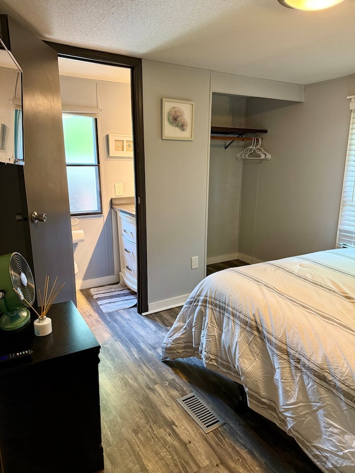 Cama tamaño queen, armario para colgar ropa y TV con medio baño