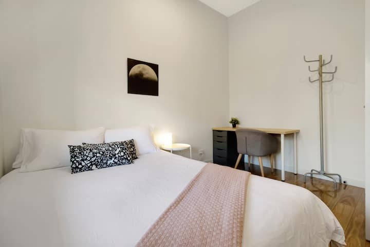 Habitación minimalista y luminosa con una cama acogedora y un espacio de trabajo dedicado