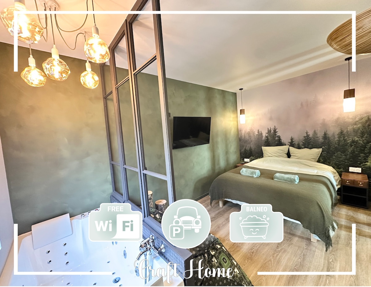 A sleek bedroom is depicted, featuring a spacious bed dressed in muted linens. A relaxing balneo area is visible, paired with modern lighting fixtures. Soft green walls create a serene ambiance, while a wall mural evokes a natural forest landscape, contributing to the overall tranquil setting.