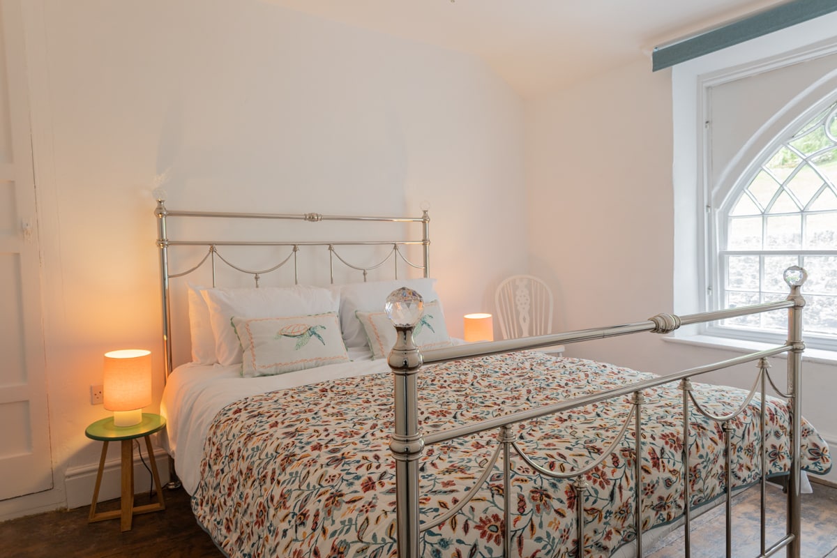 Dhomë gjumi e ndriçuar me një mbulesë krevati të rehatshme me motive dhe ndriçim të butë