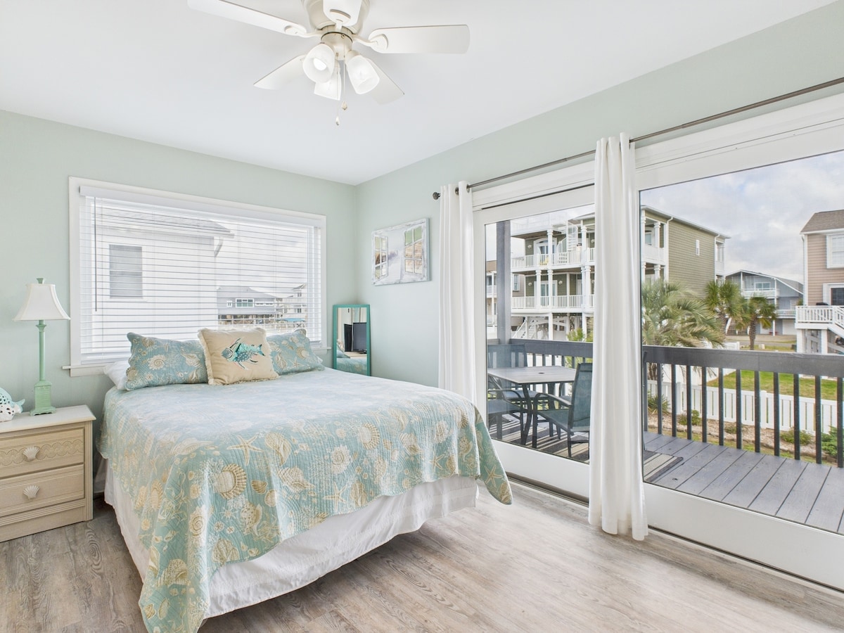 First floor bedroom features a Queen bed, smart TV and access to a shared full bathroom. Also has access to the covered deck with dining table and rockers.