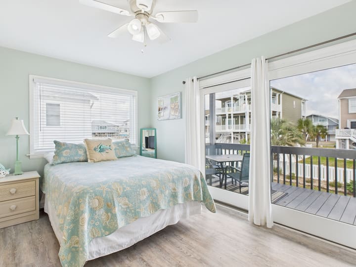 First floor bedroom features a Queen bed, smart TV and access to a shared full bathroom. Also has access to the covered deck with dining table and rockers.