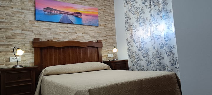 A 1.35 m x 1.95 m double bed with a headboard and 2 rustic style solid wood tables 