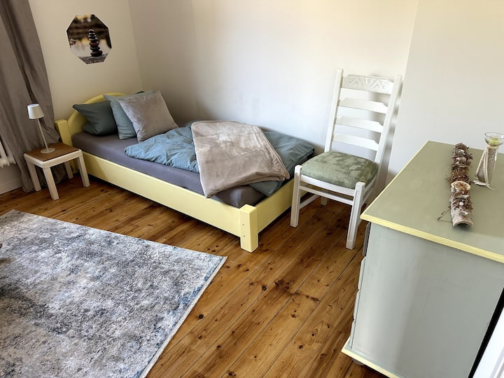 „Farbenfrohe Träume: Auch hier ist jedes Möbelstück ein handgefertigtes Unikat. Das Zusammenspiel aus sonnigem Gelb und warmen Salbei macht dieses Zimmer zu einem echten Gute-Laune-Ort."