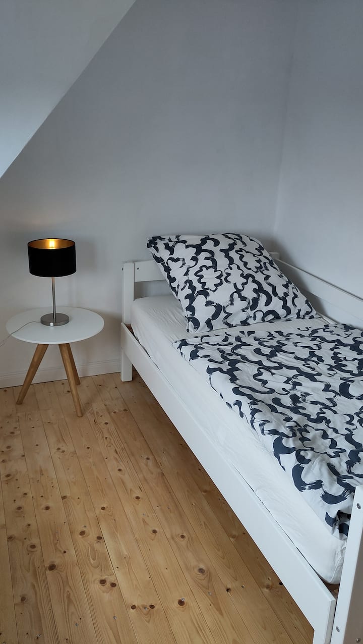 חדר שינה קטן עם שולחנות ומדף.
המיטה היא 90x200. על פי בקשה, ניתן להוציא את המיטה ולהוסיף מזרן בגודל 140x200.