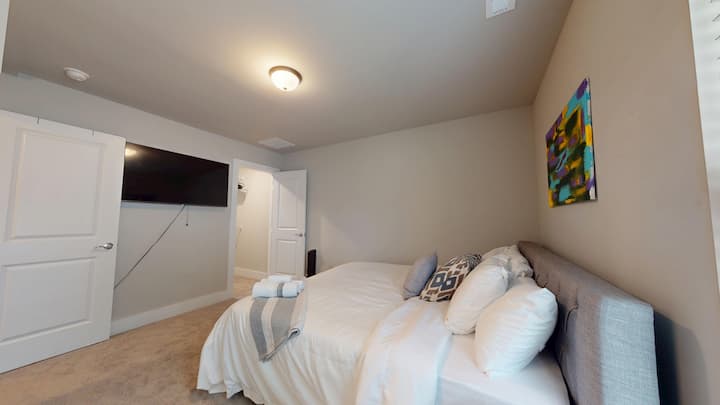 Dormitorio principal en el tercer piso con una lujosa cama tamaño king. Incluye un televisor inteligente de 43 pulgadas, un vestidor con una tabla de planchar y una plancha, y un baño adjunto con un tocador doble para mayor comodidad y conveniencia.