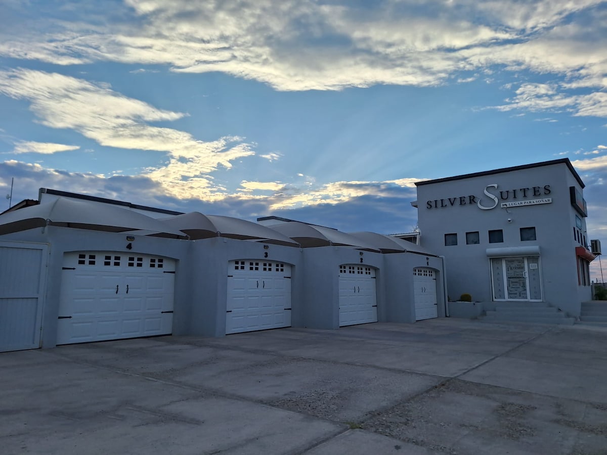 The exterior of the building features a contemporary design with multiple garage doors and large windows. The sky showcases a blend of blues and whites, hinting at sunset or sunrise, while a smooth concrete surface leads to the entrance.