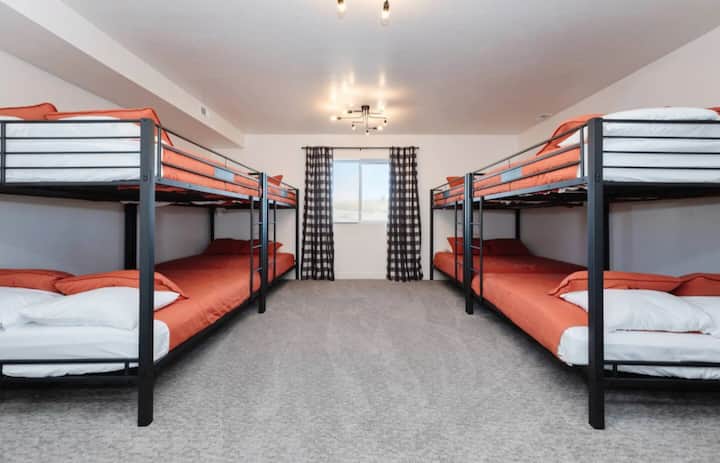 Quarto com beliche localizado no subsolo, ao lado da sala de estar do subsolo. Inclui um espelho e uma estante com livros infantis.