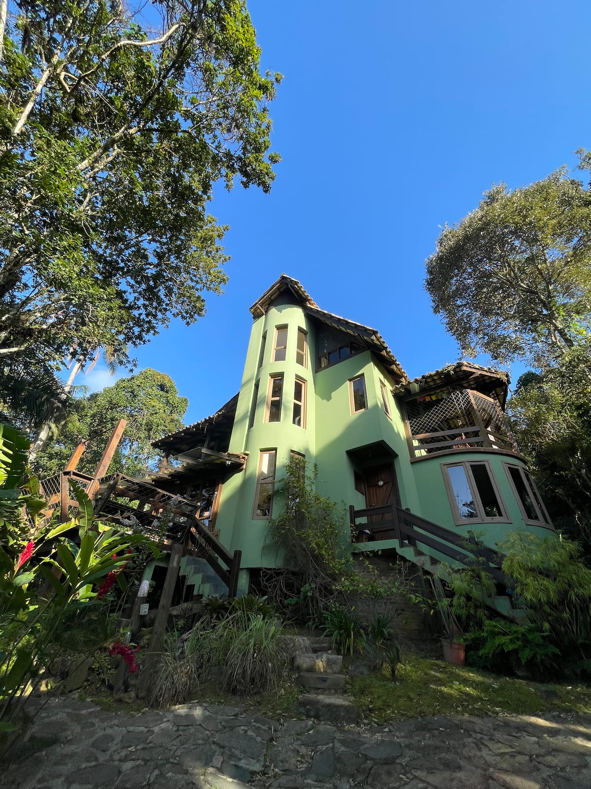 Fachada verde da Casa Encantos da Conceição cercada pela mata