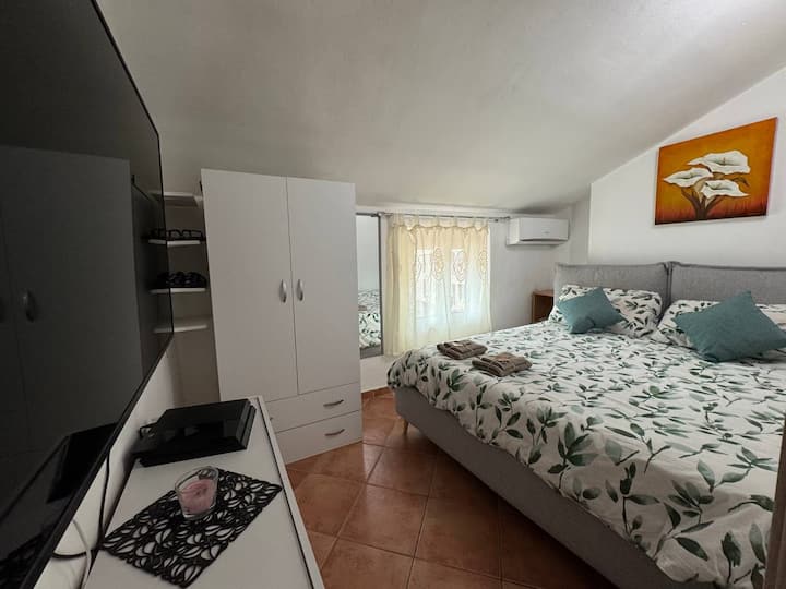 Chambre principale avec télévision home cinéma et streaming (Netflix, Prime, Disney+), grand placard et commode, lit double avec linge de lit doux, fenêtre lumineuse et climatisation chaud/froid pour un confort idéal en toute saison.