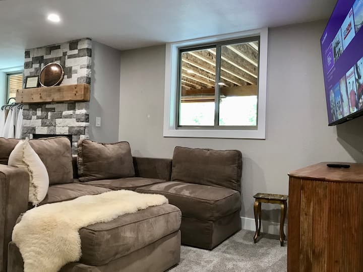 Me një oxhak me gaz, divan të rehatshëm LoveSac, televizor 65"dhe hapësirë të hapur që të çon në një aneks kuzhine dhe katër krevate.