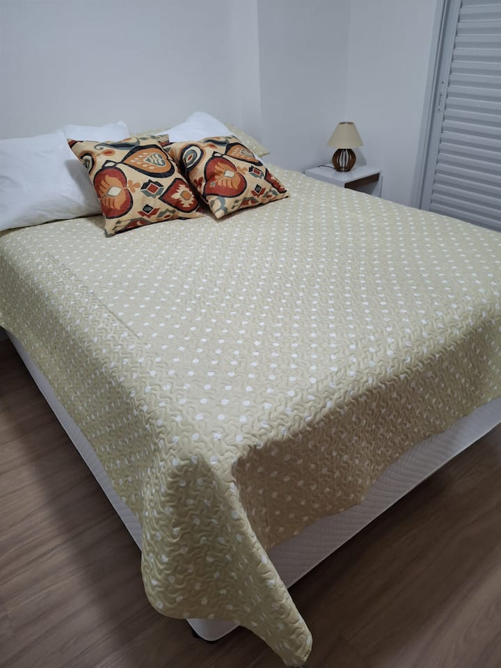 Cama doble y dos mesitas de noche con lámpara.