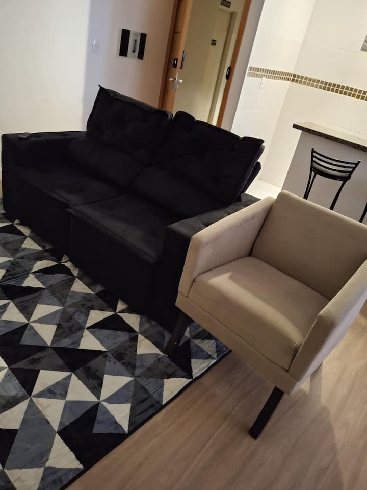 La sala de estar tiene una alfombra, un sofá retráctil y una poltrona.