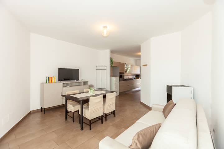 Séjour lumineux avec canapé, TV à écran plat et table à manger pour 6 personnes. Espace ouvert relié à la cuisine, idéal pour des moments de convivialité et de détente en famille ou entre amis.