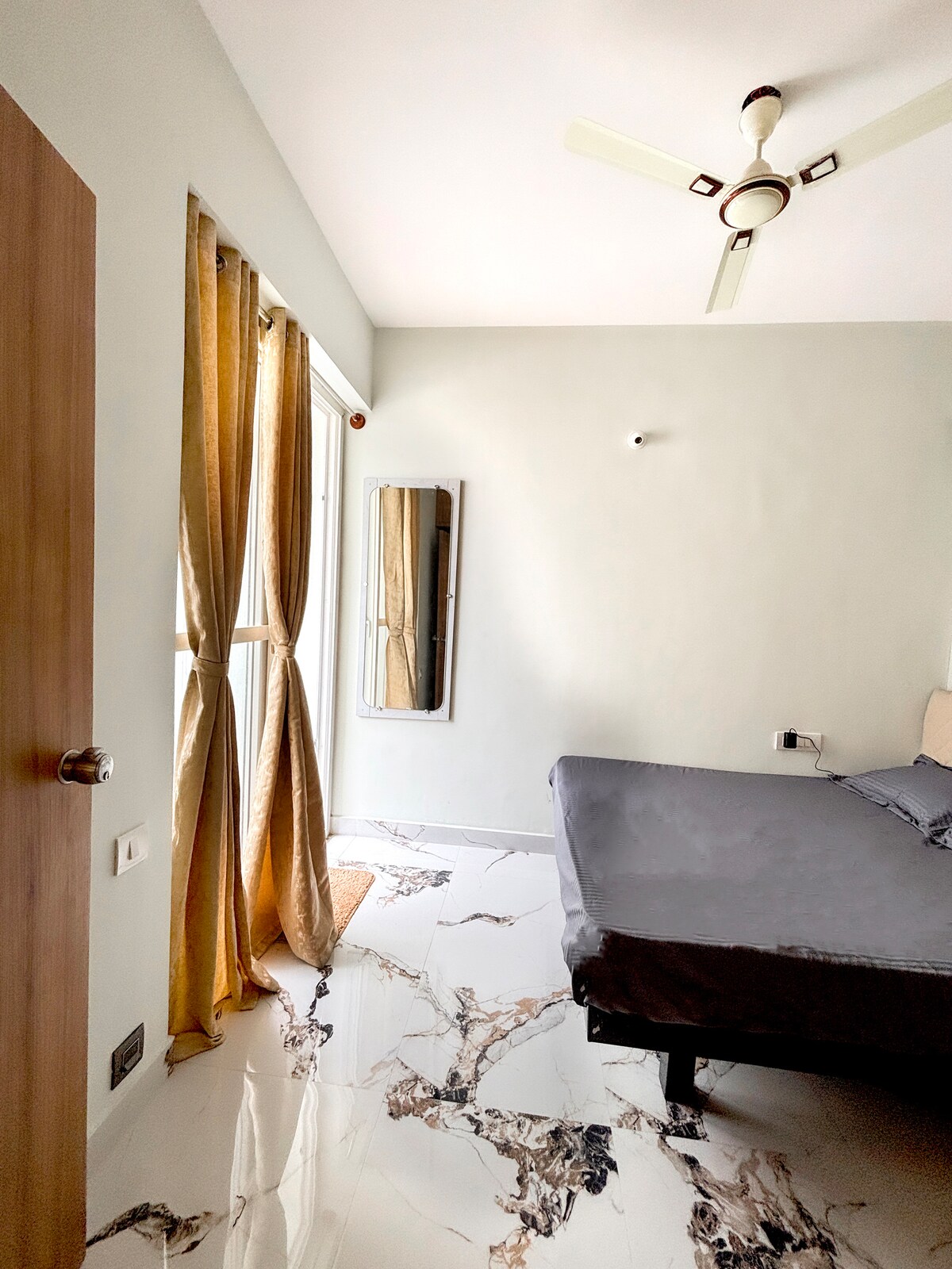 Udobna spavaća soba – jednostavna, uredna i dobro osvijetljena sa zidnim ogledalom za praktičnost.