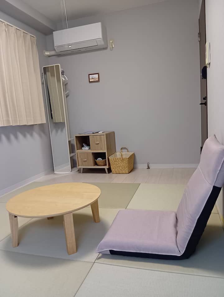 Il y a un porte-manteau avec un grand miroir, un coffre, un mini-réfrigérateur, un chabudai et une chaise.