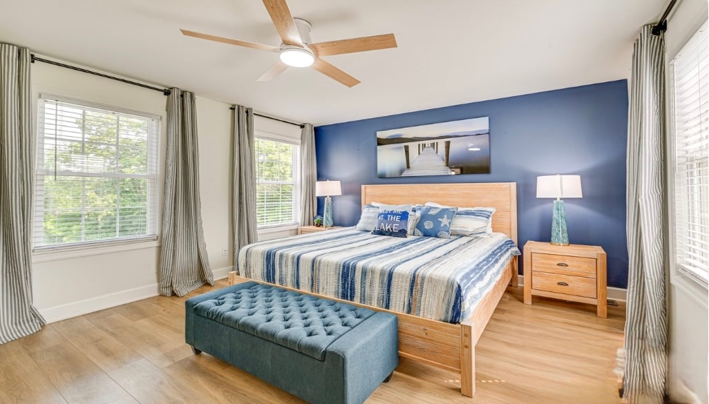 El dormitorio principal cuenta con una lujosa cama tamaño king con almohadas suaves, medianas y firmes para una máxima comodidad. Un ventilador de techo mantiene el ambiente fresco, mientras que un espejo de cuerpo entero y un televisor inteligente de 65 pulgadas añaden elegancia moderna a este refugio en Lake Linville. 