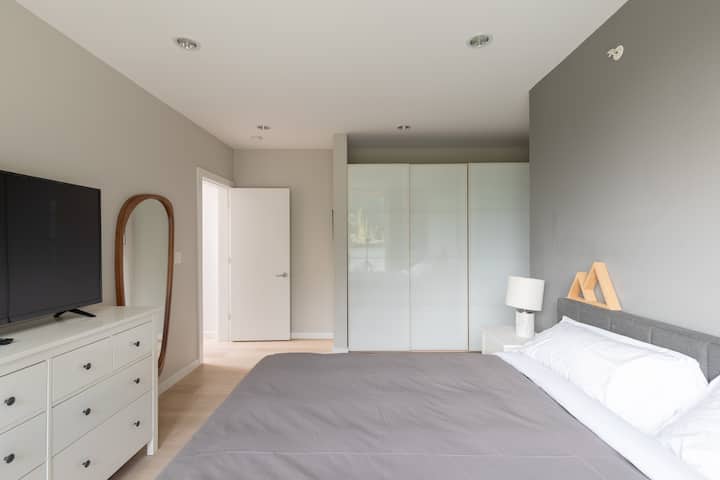 Dormitorio principal con cama tamaño king, TV inteligente, baño completo con ducha y bañera profunda.