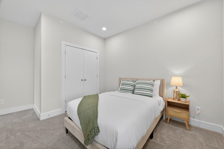 Camera degli ospiti luminosa e confortevole con letto matrimoniale, illuminazione calda e rilassanti toni neutri.