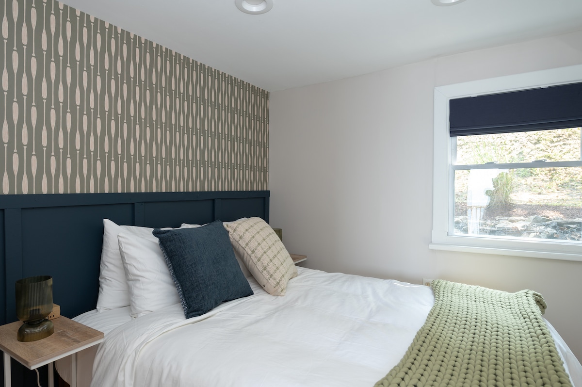 Queen bed with bedside lamps and charging cubes on either side of the bed. 