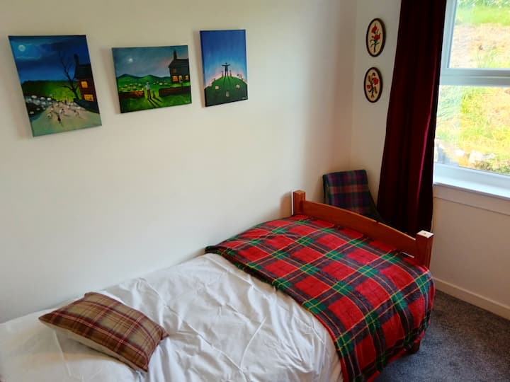 Beautifully decorated bedroom with a single bed, wardrobe, drawers and chair.