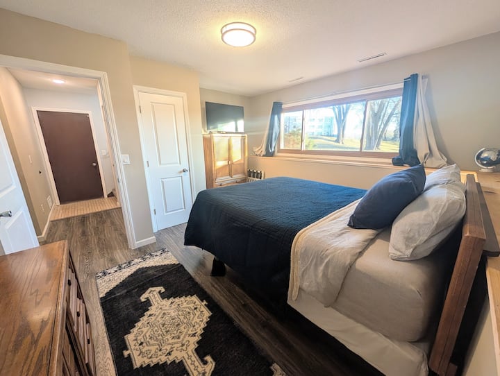 ห้องนอนชั้นล่างขนาดใหญ่พร้อมทีวีและที่นอนเมมโมรี่โฟมเนคตาร์ขนาดควีนไซส์ ตู้เครื่องแป้งและตู้เสื้อผ้ามีพื้นที่เก็บของมากมายสำหรับของของคุณ หมอนเสริม ผ้าห่ม พัดลม เครื่องทำความร้อน เตารีด และโต๊ะรีดผ้าอยู่ในตู้เสื้อผ้า 