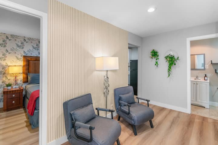 Casita privada con sala de estar, 2 camas individuales, un moderno detalle de pared con listones, iluminación ambiental y un acogedor rincón de descanso.