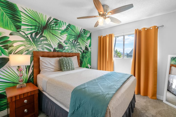 Dormitorio 3 con cama queen, mural tropical llamativo, televisión inteligente y espacio de trabajo dedicado: un cómodo refugio privado para 2 huéspedes.