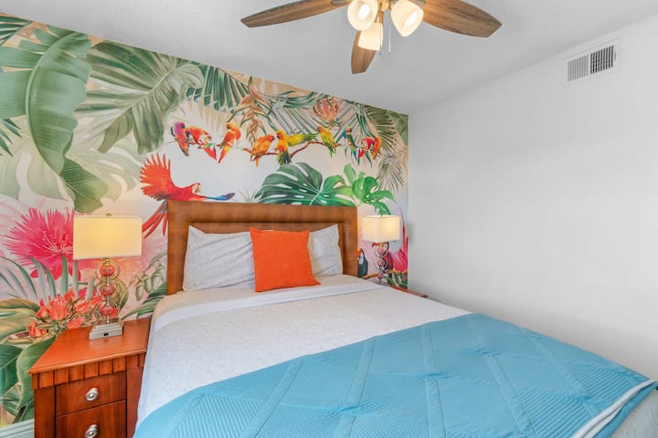 Dormitorio 4 con cama queen, un vibrante mural de aves tropicales, televisión inteligente y una decoración alegre y colorida: divertido y cómodo para 2 personas.