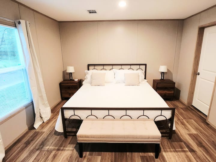 [Owner's Suite] The primary bedroom features a plush king-size bed, a large window that fills the space with natural light, and a private ensuite bathroom for your comfort and convenience.