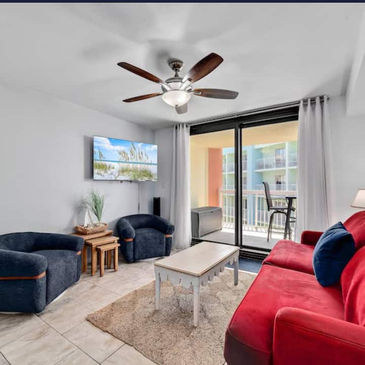 {SALA DE ESTAR} Relájate en la acogedora sala de estar con un lujoso sofá, iluminación cálida y fácil acceso al balcón. Perfecto para disfrutar de una noche fresca de otoño, tomar un chocolate caliente, ver una película o salir a disfrutar de la brisa del océano.