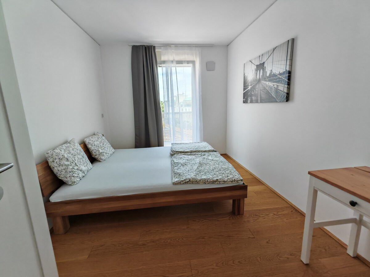 غرفة نوم ثانية بسرير مزدوج كبير الحجم ومكتب وخزانة، مع إمكانية الوصول إلى الشرفة