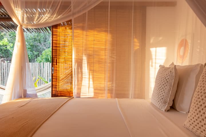 Стая, обляна в мека вечерна светлина, с леки тъкани, балдахин с мрежа против комари и балкон, интегриран с природата. Перфектно място за отдих и спокойствие.