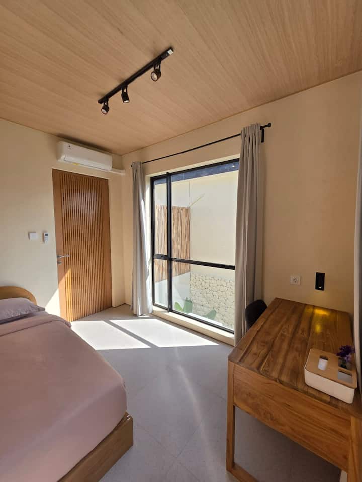 Despertarse es una delicia en este dormitorio bañado por el sol, con una cama tamaño queen enmarcada por una cálida cabecera de madera y mesitas de noche a juego. La habitación está decorada con arte de pared tejido artesanal y elegantes luces colgantes.