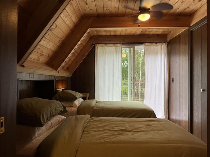 ห้องนอนชั้นหลัก มีเตียงแฝด 2 เตียง ประตูกระจกบานเลื่อนที่นำไปสู่ระเบียงด้านหลัง 