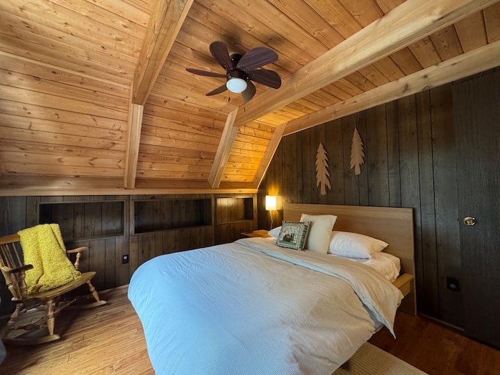 ห้องนอนชั้นหลัก เตียงควีนไซส์ ประตูกระจกบานเลื่อนที่นำไปสู่ระเบียงด้านหลัง 