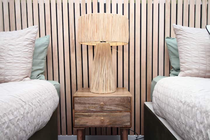 Hermoso dormitorio doble diseñado para la comodidad y la calma. Con dos lujosas camas individuales con sábanas de primera calidad, elegantes cabeceras de madera y suaves tonos neutros, el espacio se siente moderno y acogedor.