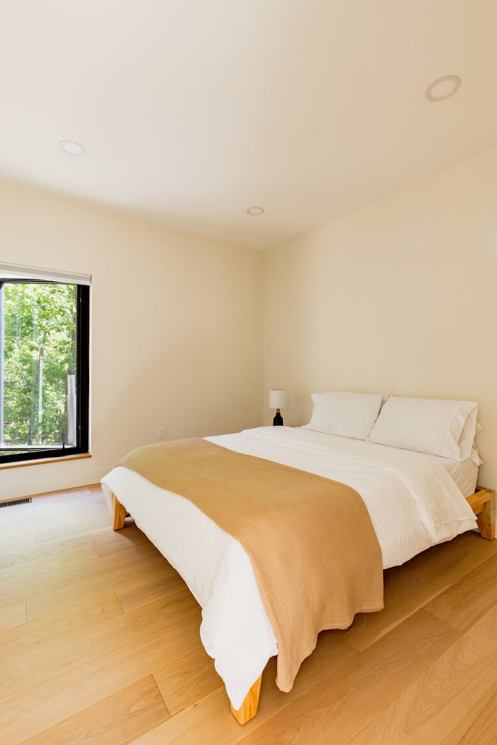 Cozy queen bed with forest views and natural light bedroom.